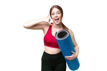 Wall Mural - Young sport woman going to yoga classes while holding a mat over isolated chroma key background making phone gesture. Call me back sign