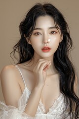 Wall Mural - Young Asian Woman with Long Hair Holding Hand Cream in White Dress on Beige Background - Korean Makeup, Red Lips, High Resolution Portrait