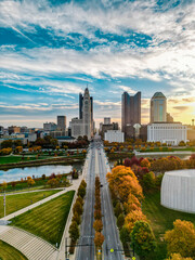 downtown columbus ohio at dawn with a blue sunny sky and fall autumn colors on the trees along the river with an open road during the early commute