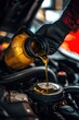 © Anna - a car mechanic pours oil into a car engine. Selective focus