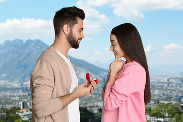 Wall Mural - Man with engagement ring making marriage proposal to his girlfriend. Couple against cityscape