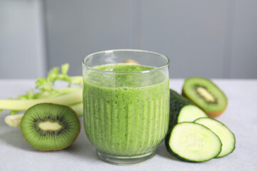 Delicious green smoothie and ingredients on light table, closeup