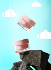 Sticker - Jars, stones and clouds on light blue background. Poster or flyer design for cosmetic cream