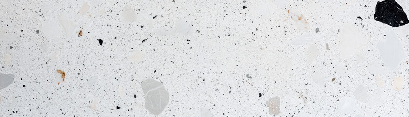 A close-up view of a light terrazzo floor featuring a mix of small, colorful stone fragments set in a white concrete background. Great for texture and design use.