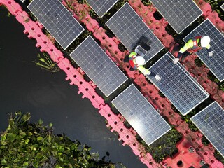 Male workers repair Floating solar panels on water lake. Engineers construct on site Floating solar panels at sun light. clean energy for future living. Industrial Renewable energy of green power.