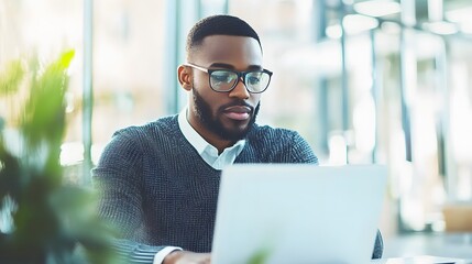 Wall Mural - A Man in Glasses Works on His Laptop in a Modern Office Setting