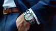 © sungedi - A silver wristwatch on the wrist of a man wearing a blue suit and white shirt
