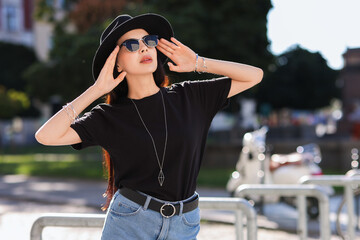 Sticker - Young woman in stylish black hat and sunglasses on city street