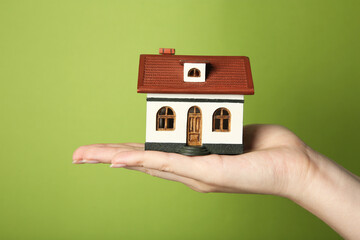 Wall Mural - Woman with house model on green background, closeup