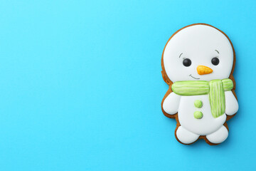 Wall Mural - Tasty Christmas cookie in shape of snowman on light blue background, top view. Space for text