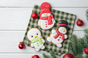 Poster - Delicious cookies in shape of snowmen and Christmas decor on white wooden table, flat lay. Space for text