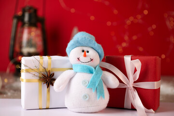 Wall Mural - Funny snowman figure and Christmas gifts on white table