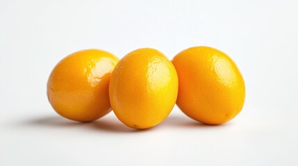 Three shiny yellow lemons arranged closely on a white surface.