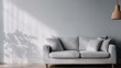 © Dulemegapixel - A minimalistic modern living room featuring a comfortable grey upholstered sofa with sunlight streaming in and a hanging wicker lamp, creating a serene and inviting atmosphere.