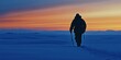 © jambulart - A lone hiker walks through snowy landscape at sunset.