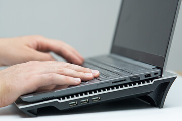 Close up of male hand using laptop standing on cooling stand