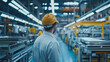 © Budsadee - Industrial production line for automotive parts, workers monitoring the process, bright factory lights