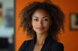 © julija - vibrant businesswoman portrait confident pose against bold orange backdrop