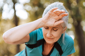 Wall Mural - Senior woman feeling tired after exercising outdoors in the park