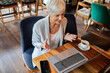 © Davor - Senior businesswoman having video call on laptop in cafe