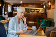 © Davor - Senior businesswoman having video call on laptop in cafe