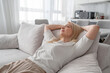 © Николай Амосеев - A woman relaxing on a sofa in a modern living room, enjoying a moment of calm and contentment