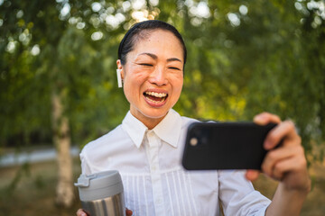 Wall Mural - Mature japanese woman watch funny videos on mobile phone in the park