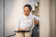© Miljan Živković - japanese businesswoman sit on staircase hold clipboard and thermos