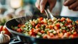 © Dulemegapixel - A close-up shot of a hand stirring a mixture of fresh, diced vegetables in a pan, representing the vibrancy, freshness, and satisfaction of home-cooked meals and culinary expertise.
