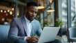 © sungedi - A Black Man Working on a Laptop in a Modern Office Setting