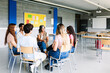 © Xavier Lorenzo - Young group of teenage students discussing in classroom sitting in circle with female teacher, giving an opinion on a debate topic. Education concept