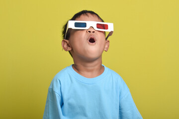 Asian boy surprised wearing 3d glasses, Watching movie isolated on yellow background. Watching movie and cinema concept