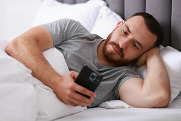 Poster - Handsome man using mobile phone in bed