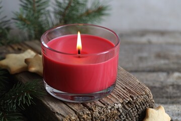 Wall Mural - Burning candle, Christmas cookies and fir tree branches on wooden table, closeup