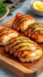 © Seksan - Grilled seafood served on a wooden platter, featuring succulent lobster tails garnished with herbs and lemon slices.