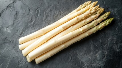 A top view of fresh white asparagus, neatly peeled and placed on a slate background. The clean, natural look of the spears is perfect for culinary visuals.