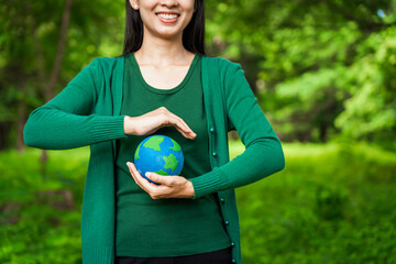 Forest conservationist holds small globe in hands, symbolizing global responsibility for protecting  planet. Standing outdoors in green park, sustainability, commitment to achieving net-zero impact.