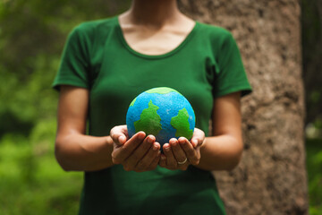 Forest conservationist holds small globe in hands, symbolizing global responsibility for protecting  planet. Standing outdoors in green park, sustainability, commitment to achieving net-zero impact.