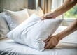 © Jason - Hand placing white pillow on bed in morning