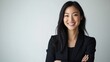 © Adi - A Smiling Asian woman in black business attire radiates professionalism and approachability, with her well lit face showcasing expressions of confidence and poise on white background