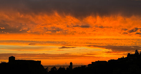 Wall Mural - Dramatic sunset sky above dark old town at night 