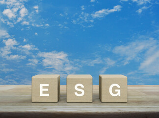 ESG acronym on wood block cubes on wooden table over blue sky with white clouds, Environmental Social Corporate Governance concept