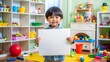 © onehourhappiness - Playful Asian Child Holding Blank Poster in Vibrant Playroom. Creative Learning Moment