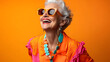 © Daniel - Happy senior woman in colorful orange outfit, cool sunglasses, laughing and having fun in fashion studio