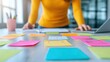 © Enjoy - A person in yellow sweater is focused on brainstorming with colorful sticky notes spread across table, creating an engaging and collaborative atmosphere