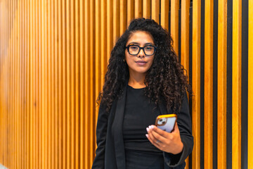 latin businesswoman in black elegant clothes using mobile phone