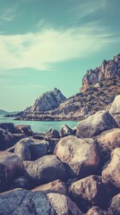 Canvas Print - Rocky shoreline with blue water and a mountain backdrop.