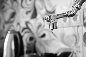 Water dripping from faucet close-up on home kitchen. Lack of clean water, reckless use of resources.