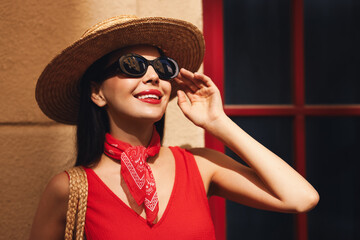 Poster - Smiling young woman in stylish hat and sunglasses near building outdoors