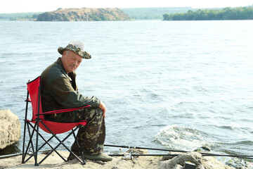 Sticker - Fisherman with rod sitting on chair and fishing near lake at summer, space for text